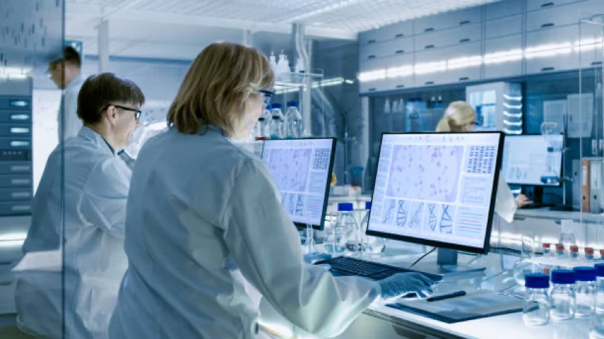 two doctors standing in front of two computer screens in a medical biology lab
